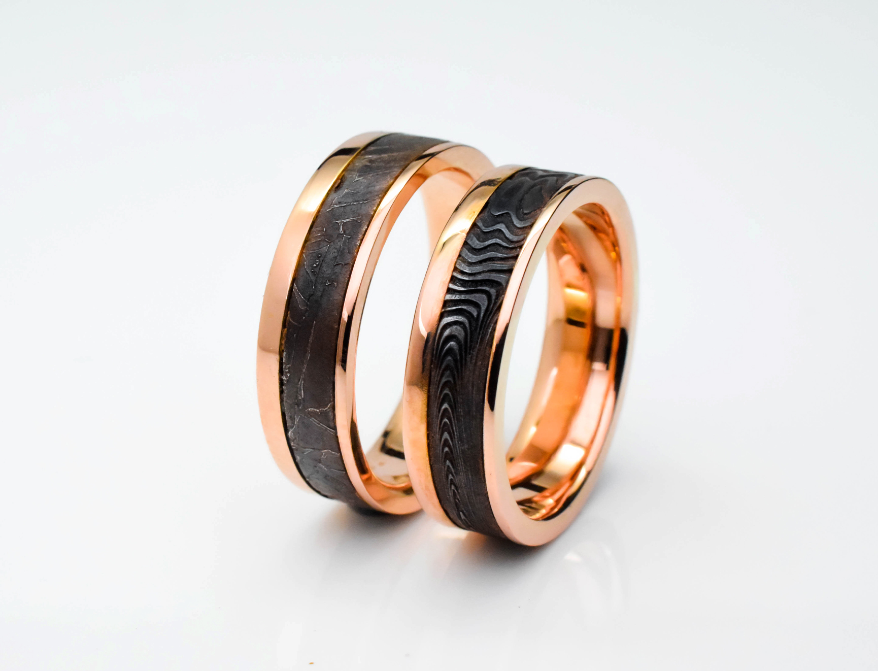 Pair of rose gold wedding rings with damascus steel