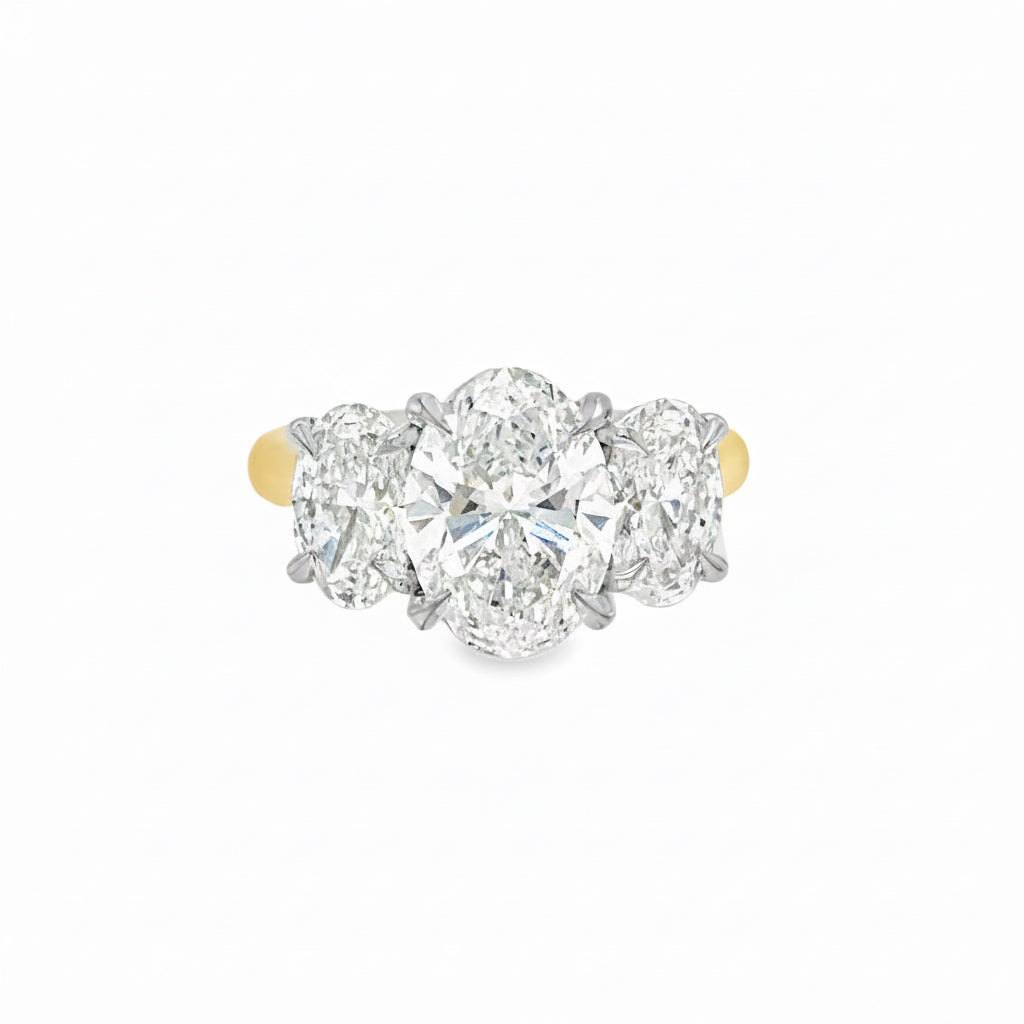 A three-stone 5.04 carat diamond ring featuring a large oval center diamond flanked by two round side diamonds