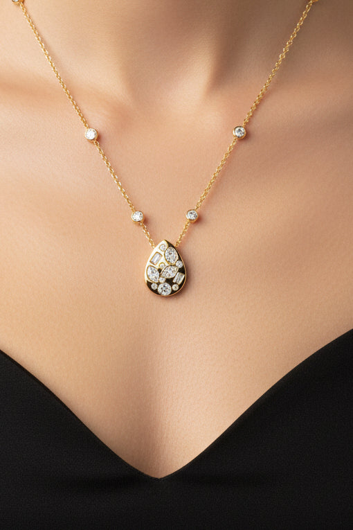 A gold necklace featuring a teardrop-shaped pendant adorned with multiple round and baguette-cut Natural Diamo